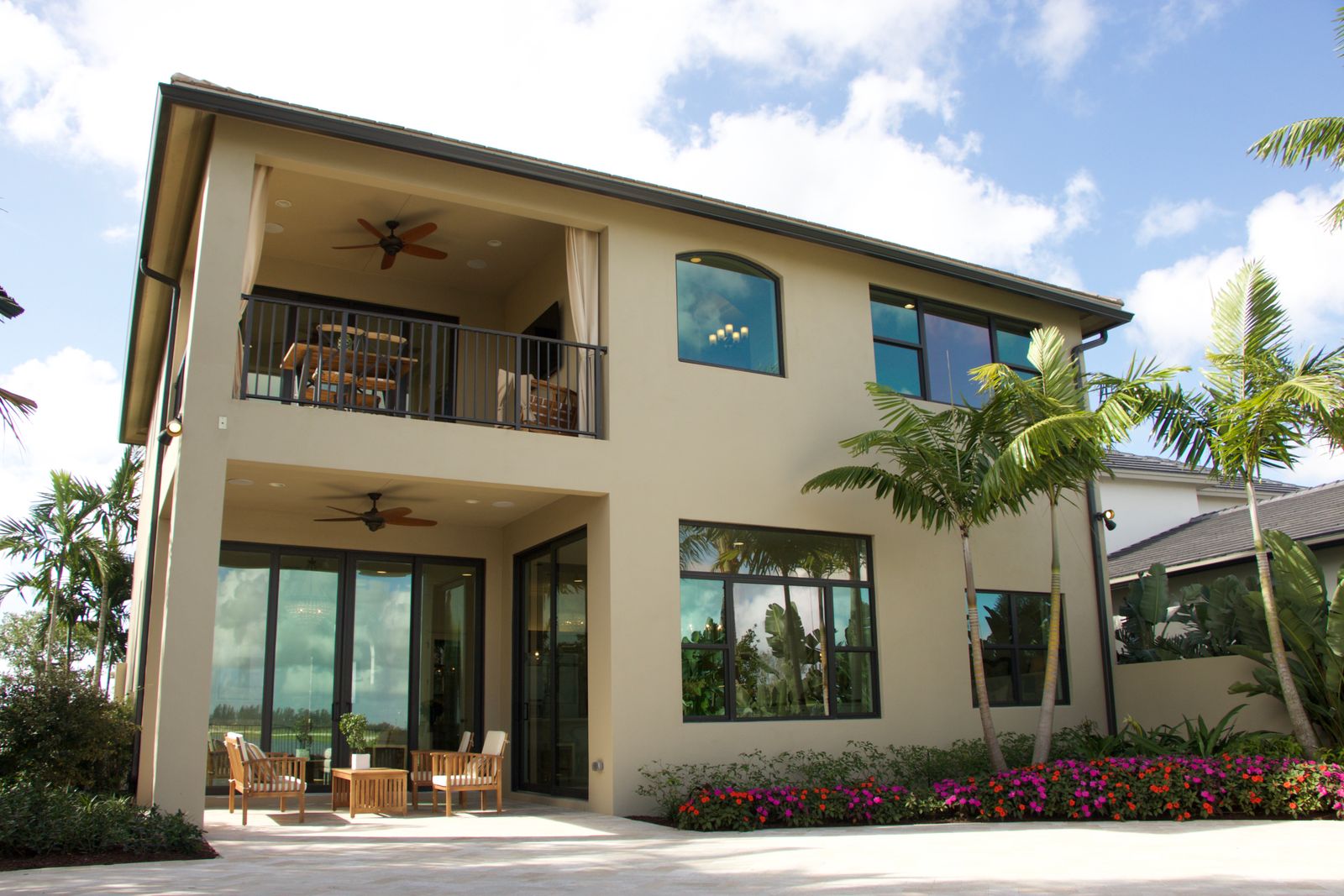 Light stucco home with a balcony, patio, and palms